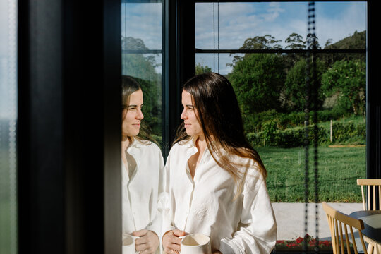 Woman standing contemplatively beside her reflection