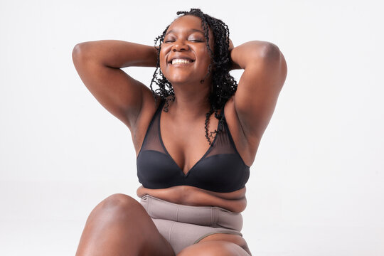 Smiling woman in bra and underwear, hands behind head.