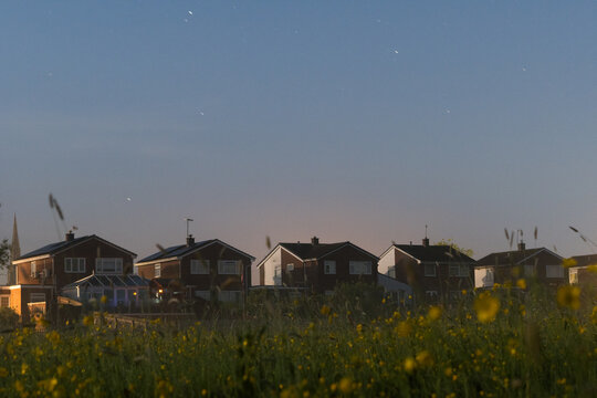 A row of houses on the edge of a meadow at night