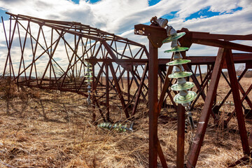 Old rusty transmission line support dumped in a field for dismantling, a pile of rusty iron and...