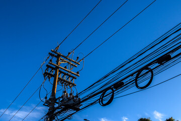 Many wires attached to the electric pole, the chaos of cables and wires on an electric pole, blue...