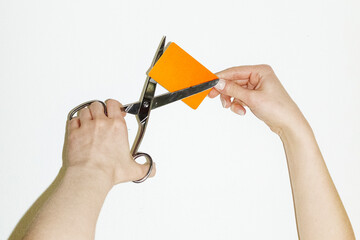 Person cutting payment credit business card with silver scissors 