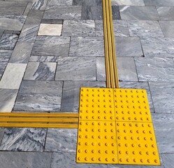 tactile patterns and yellow markers on flooring assist visually impaired individuals in navigation....