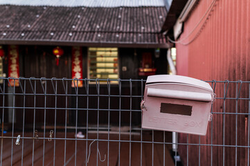 Pink mailbox on metal fence in front of chinese house