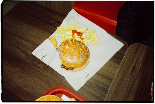 french fries and nibbled hamburger on a table, 35mm