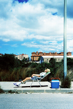 a man in summer clothes resting on a sunlounger on the street, 35mm