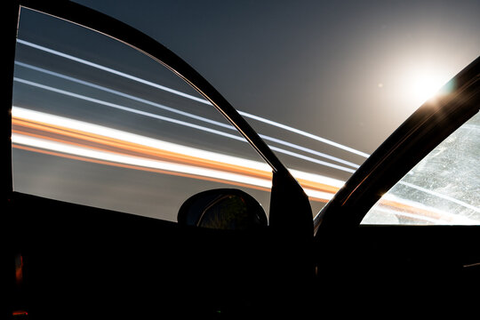 A parked car with traffic trails through the car window 