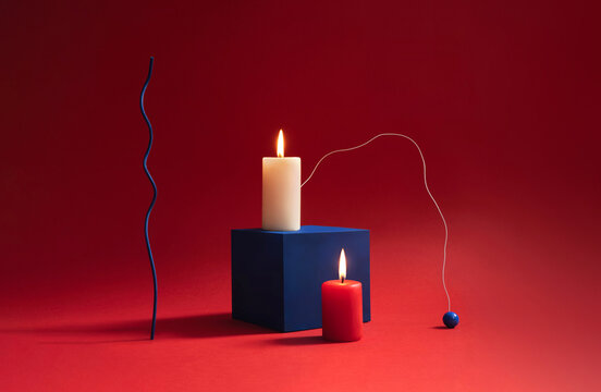 Red and white candles against a bold red background.