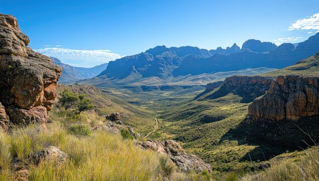 Mountain valley vista,  sun-drenched landscape.  Rocky outcrops frame a verdant valley, winding road visible