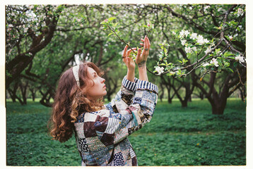 Woman in a patchwork jacket admires blooming flowers