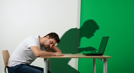 Exhausted worker slumps over desk, laptop nearby, while a shadowy figure seems to control his computer.