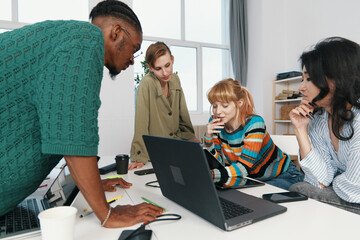 Fototapeta premium Young adult woman and colleagues working together in a modern workplace, socializing and collaborating on a business project with Gen Z coworkers.