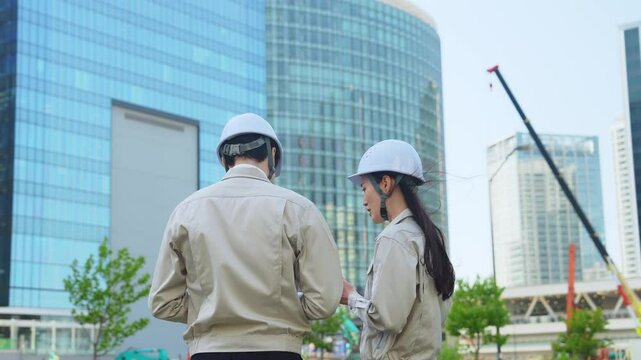 A group of male and female engineers having a meeting while looking at a tablet at a construction site