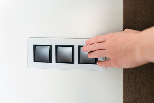 Touching a Sleek Light Switch in a Modern Home Design