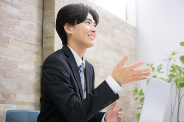お客様に説明する若手の営業マンなどのイメージ　説明やプレゼンの横顔