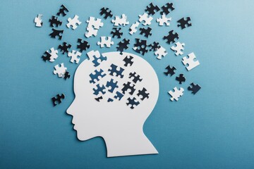 A white head silhouette, brain puzzle scattered