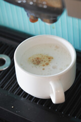 Coffee brewing in a white mug on a countertop