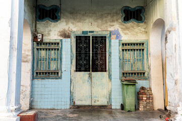 Faded blue tiled facade with iron grille and patina