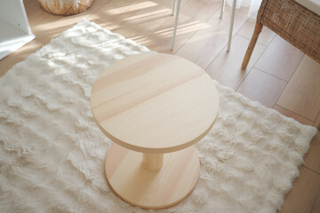 Modern wooden table placed on soft rug in bright room