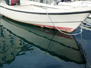 Serene scene with small boat bobbing on gentle ocean waves and reflection in water
