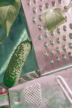 Unique arrangement of a cucumber beside a kitchen grater