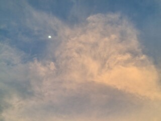 Soft Evening Clouds and a Gentle Moon Glow in the Tranquil Sky at Sunset's Golden Hour