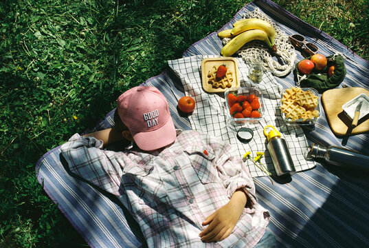 Unrecognizable girl lying on a picnic  blanket at summer.
