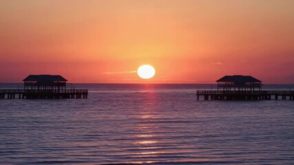 Beautiful sunset over two fishing piers by the calm sea in a serene location