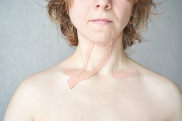 Young caucasian female with therapeutic tape on neck for pain relief and support.