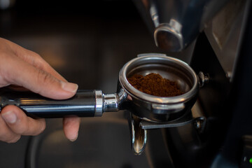 Barista fill the portafilter with coffee grounds to make espresso	