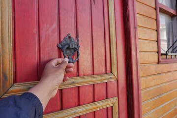 Hand reaching for door knocker on wooden door