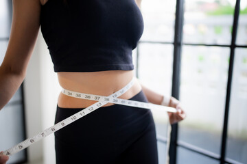 Asian healthy woman dieting Weight loss. Slim woman measuring waist with measure tape after diet at...