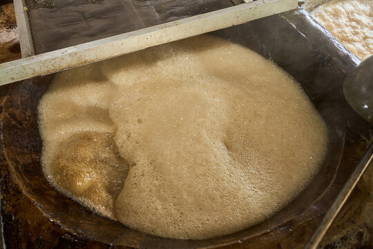 Sugar cane juice boiling in large container during processing