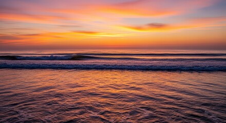 Obraz premium A serene sunset over a calm ocean with soft waves and golden light