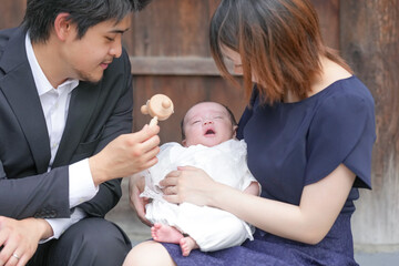 In June 2025, a young Japanese couple in their early twenties sits on a stone wall at a shrine in...