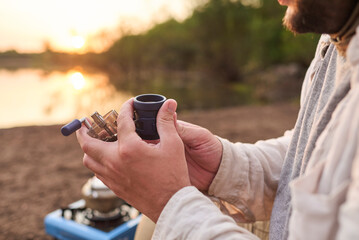 Traveler grinding coffee beans in his portable grinder for breakfast outdoors at dawn, in El Palmar...