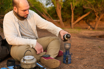 Coffee filtering process. Hispanic man making coffee for breakfast outdoors early in the morning by...