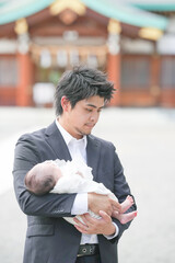 In June 2025, a young Japanese father in his early twenties holds his one-month-old baby with care...