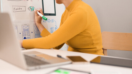 Asian Adult Woman User Interface Designer Creates Mobile App Interface Flowchart and Color Palette...