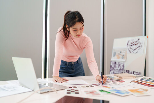 UI UX Designer Asian Woman Working on User Interface at Desk with Laptop Color Palette and Sketches for Website Mobile App Design Process Creation - Powered by Adobe