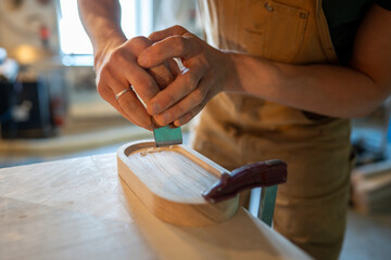 Close up master joiner hands making final polishing sanding coaster for glasses bottles in...