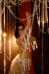 Brunette young woman, Caucasian, dressed as vintage cabaret dancer, posing front view under hanging...