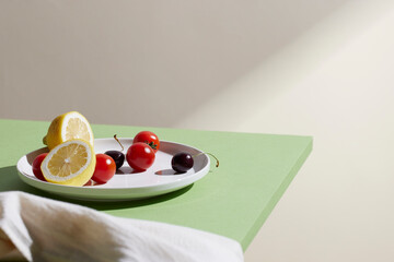 A cozy backdrop with fresh fruits and grass on a table with natural sunlight and shadows.