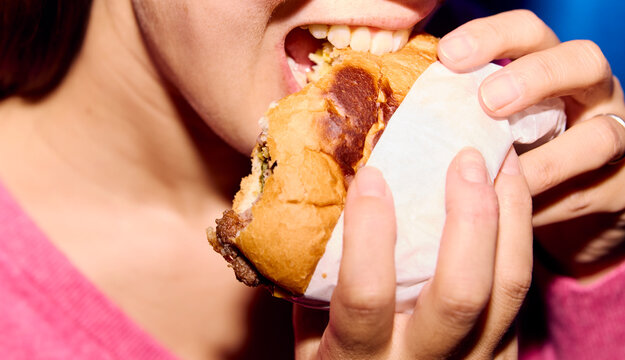 Anonymous woman bites a burger