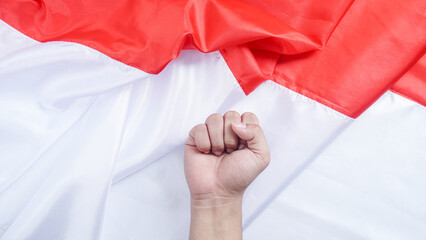 Red and white national flag of Indonesia as background for copy space with man's fist