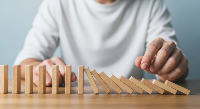 Domino Effect Illustration Hand Stopping Wooden Blocks from Falling on Tabletop for Risk Management Concept