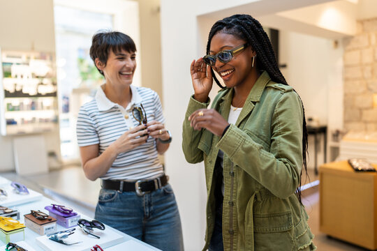 Woman trying new eyeglasses laughing with optician in eyewear store