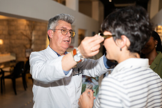 Optician helping woman choosing eyeglasses in optical store