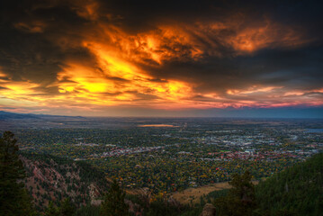 Expansive view of the Boulder, Colorado city skyline at dusk, overlooking the entire city with the Flatirons and Rocky Mountains in the background under a colorful twilight sky.
