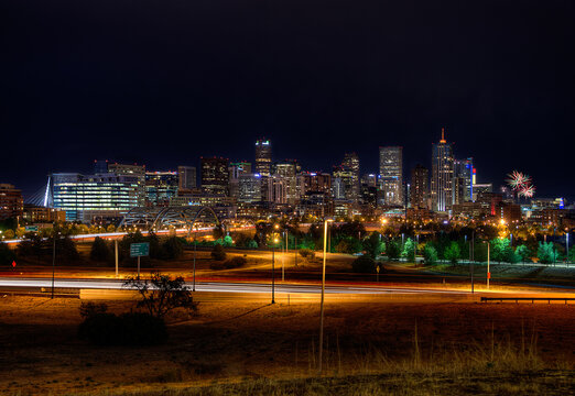 Dramatic night view of the Denver, Colorado skyline illuminated by colorful fireworks bursting in the sky, celebrating a festive event over the city’s iconic downtown buildings.